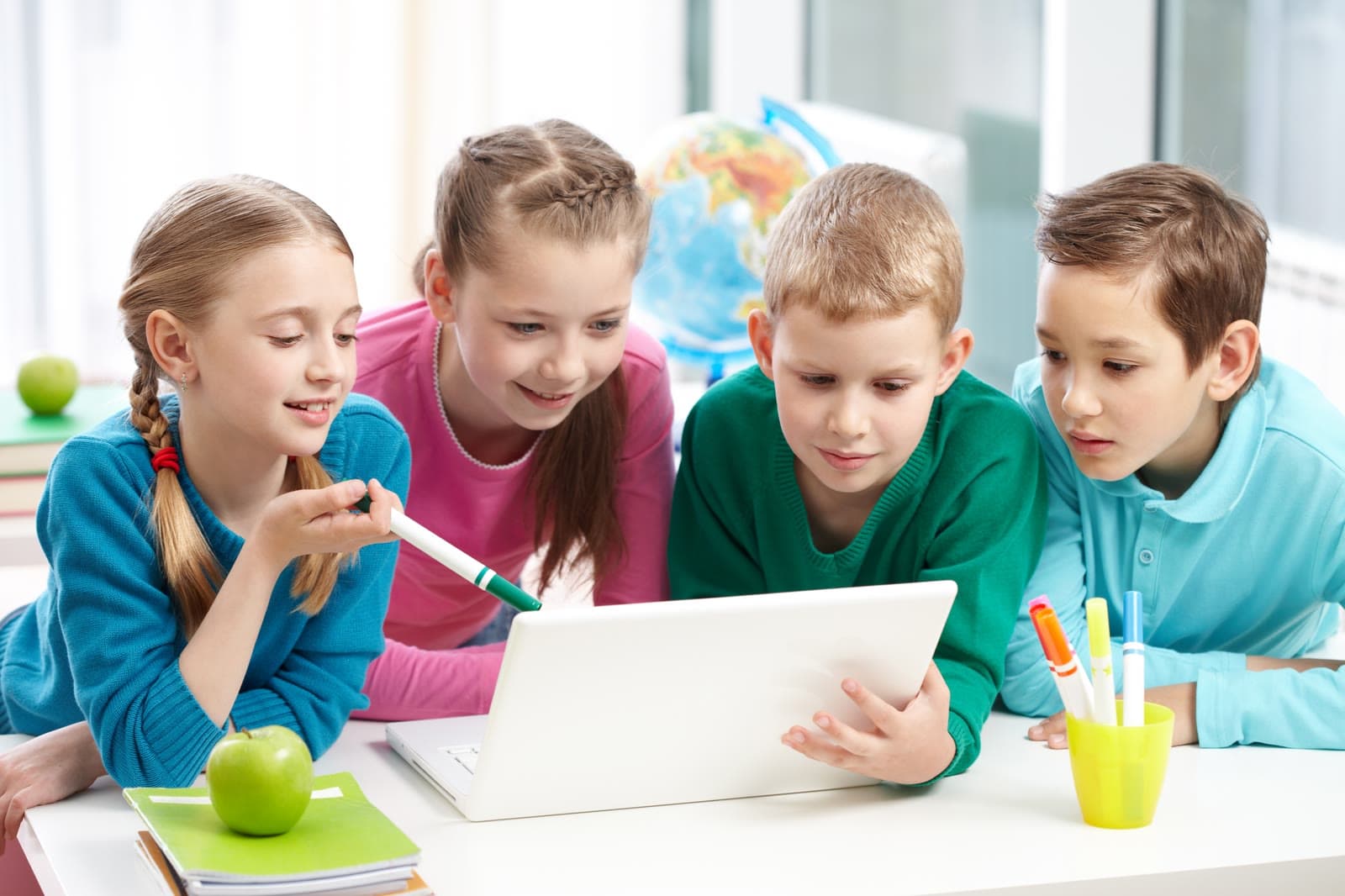 Four classmates learning together around a laptop