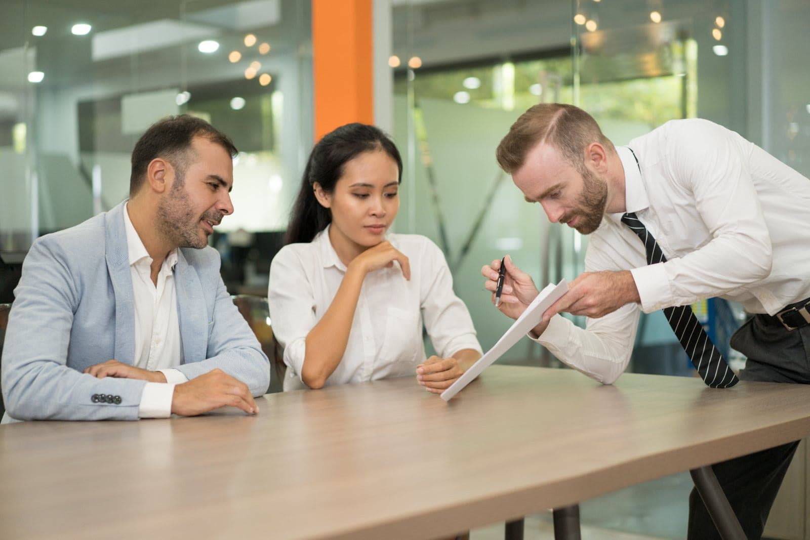 A manager reviewing a document with two seated colleagues in an office